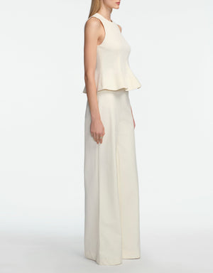 A woman stands in profile against a white background, wearing the Lela Rose Stretch Cotton Halter Top and matching wide-leg pants—a chic off-white cocktail set with tailored fit and flared hem.