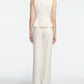 A woman stands facing away in a Lela Rose Stretch Cotton Halter Top, off-white with tailored fit and flared hem, paired with matching wide-leg trousers against a plain white background.
