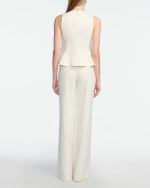 A woman stands facing away in a Lela Rose Stretch Cotton Halter Top, off-white with tailored fit and flared hem, paired with matching wide-leg trousers against a plain white background.