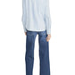 A person stands with their back to the camera, wearing a light blue long-sleeve shirt, blue Low Rise Le Slim Palazzo jeans by Frame, and black shoes.