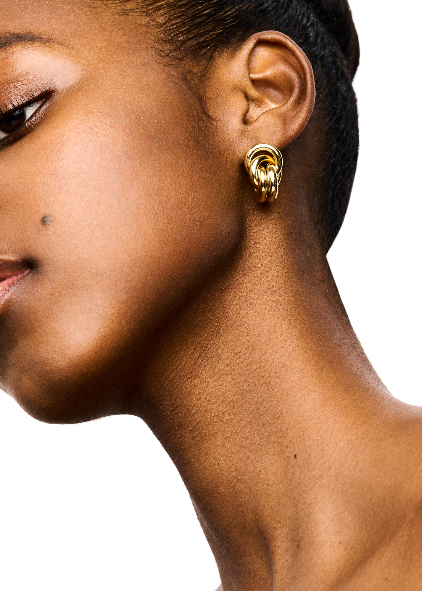 Close-up of a woman's profile showing her ear adorned with LIÉ STUDIO Vera Earrings, focusing on her smooth skin and elegant neckline.