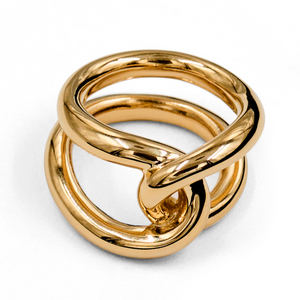 The LIÉ STUDIO Agnes Ring by Lie Studio boasts a gold intertwined loop design with a shiny, polished surface in 18 carat gold vermeil, elegantly showcased against a white background.