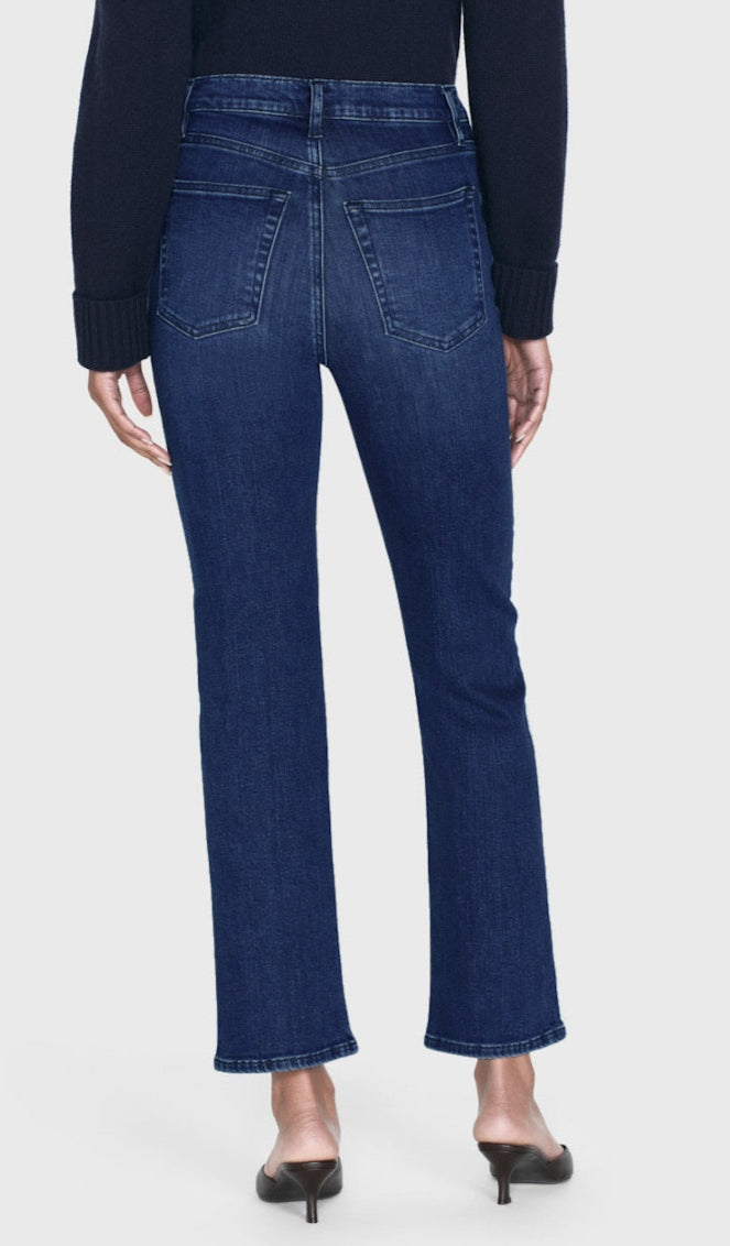 A person is shown from the back against a plain light background, wearing Frame's Le Sleek Straight high-rise, straight-leg jeans paired with heeled mules.