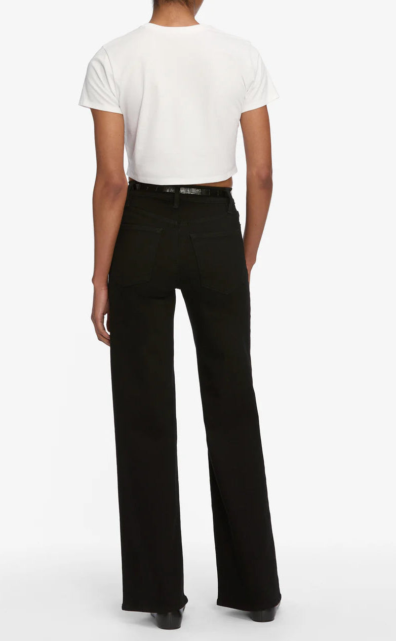 A person stands facing away, wearing a white short-sleeve crop top and FRAME Le Slim Palazzo high-rise black pants with a black belt and black shoes.