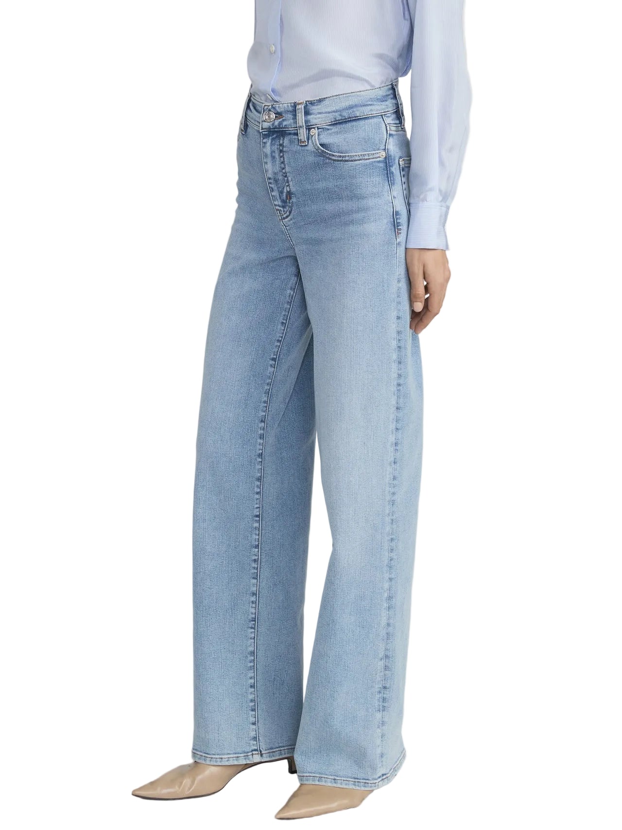 A person wearing Frame’s Le Slim Palazzo light blue wide-leg jeans and a light blue long-sleeve blouse with beige pointed-toe shoes, standing against a plain white background.
