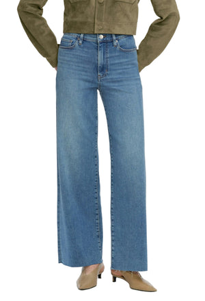 A person wears the Frame Le Slim Palazzo high-rise, wide-leg flare blue jeans, a khaki jacket, and taupe heeled shoes. The upper body and face are not shown.