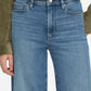 Model wearing Frame's Le Slim Palazzo high-rise blue jeans, featuring a subtle palazzo silhouette, paired with a green suede jacket; shown from mid-torso to upper thighs with one hand at their side.