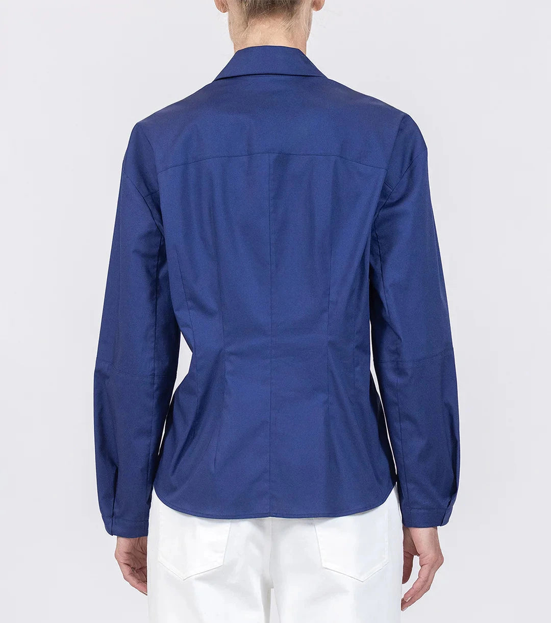 A person seen from the back wears the Callas Milano Lucia Top—a fitted, long-sleeve blue cotton poplin shirt with a collar—paired with white pants, set against a plain background.