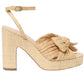 The Loeffler Randall Lucia Platform is a high-heeled sandal featuring a beige pleated design, an ankle strap, natural raffia accents, and a knotted bow on the front.