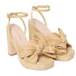 A pair of beige Loeffler Randall Lucia Platform heeled sandals with large bow details on the toes and ankle straps, isolated on a white background.