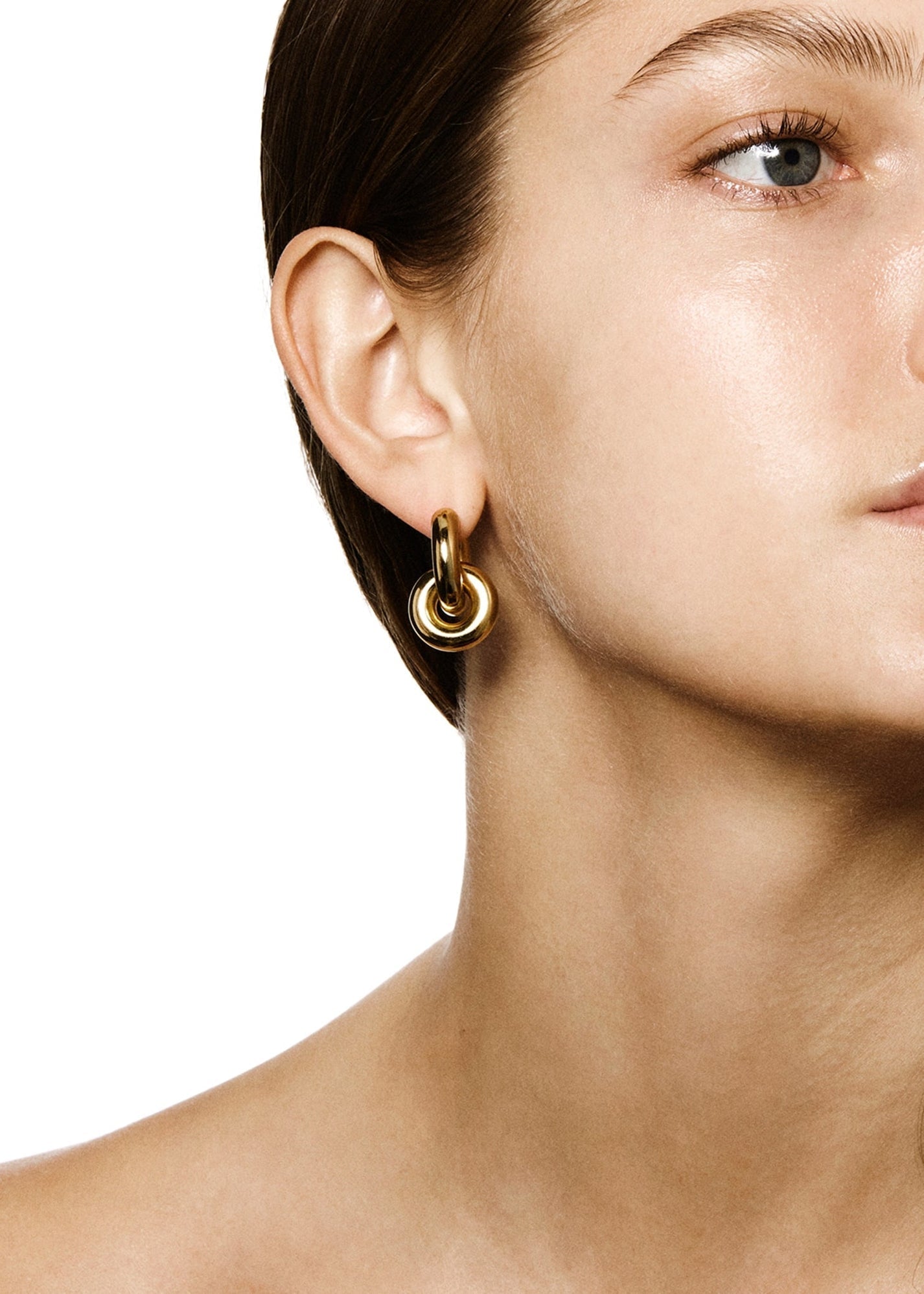 A close-up image of a person's right ear showcasing a pair of LIÉ STUDIO Esther Earrings by Lie Studio, featuring gold-plated brass hoops against a plain white background.