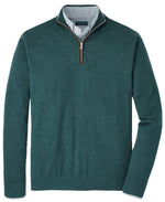 Peter Millar's Excursionist Flex Quarter-Zip Sweater in luxurious green Merino wool, layered over a checked collared shirt, is neatly arranged.