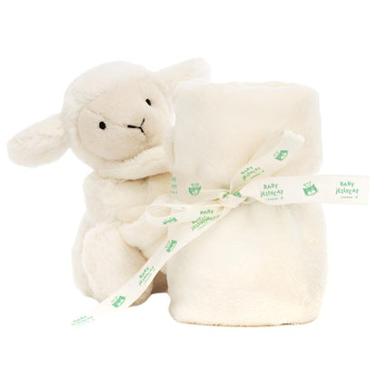 The Jellycat Bashful Lamb Soother, made from recycled fibers, sits beside a rolled cream-colored baby blanket tied with a ribbon—an ideal gift for a newborn.