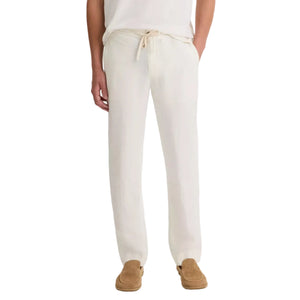 A person wearing vince Patch Pocket Drawstring Pant in off-white hemp, paired with a white shirt and tan slip-on shoes, stands with hands in pockets.