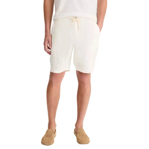 A person wears a white t-shirt, tan loafers, and vince Patch Pocket Drawstring Short—cream, breathable with a drawstring waist—standing hands-in-pockets against a white background.