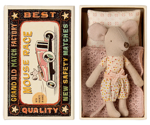 A Maileg Little Sister mouse, dressed in a charming polka-dot outfit, rests comfortably in a matchbox bed crafted from soft fabrics, nestled inside a cardboard box. The box is labeled "Maileg Little Sister, Mouse in Matchbox" and features delightful vintage matchbox-style graphics on the lid.