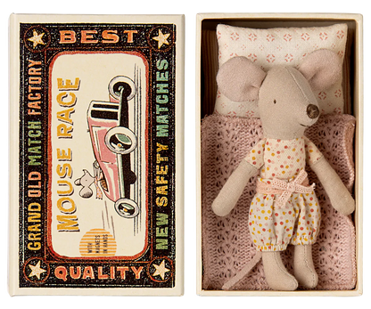 A Maileg Little Sister mouse, dressed in a charming polka-dot outfit, rests comfortably in a matchbox bed crafted from soft fabrics, nestled inside a cardboard box. The box is labeled "Maileg Little Sister, Mouse in Matchbox" and features delightful vintage matchbox-style graphics on the lid.