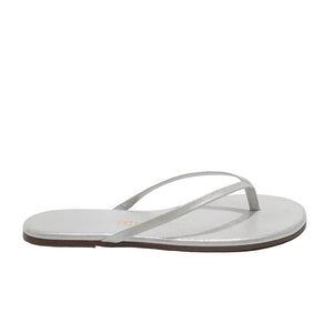 The Lily Glitters Sandal by Tkees features a single silver glittery flip-flop design with thin straps and a flat sole, shown in a side view on a white background.