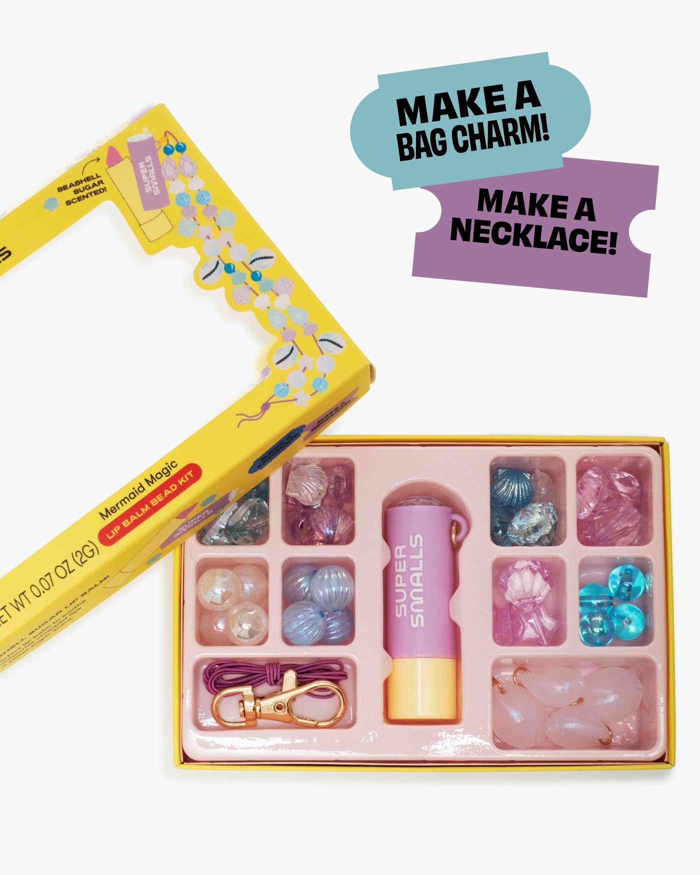 The Super Smalls Mermaid Magic Lip Balm Bead Kit includes assorted beads, a purple tube, Mermaid Magic Lip Balm, a gold bag charm, and cords—everything kids need to create their own necklace or bag charm.