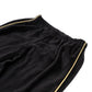 The Meri Meri Little Drummer Costume, featuring luxurious black fleece pants with gold piping and an elastic waistband that evoke a plush Christmas costume, is displayed laid flat on a white background.