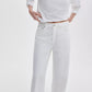 Wearing the Rag & Bone Featherweight Logan Wide jeans, a person poses with one hand on their hip, dressed in a white long-sleeve shirt against a plain white background.