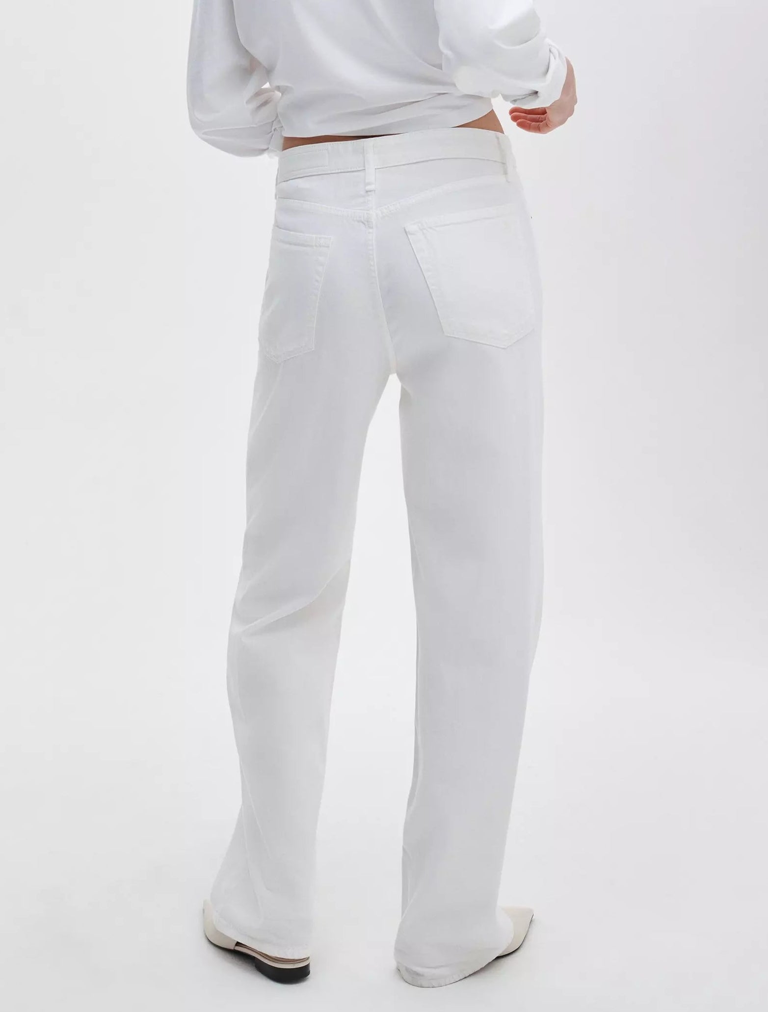 A person is seen from the back in Rag & Bone Featherweight Logan Wide mid-rise jeans and a white long-sleeve top, set against a plain white background.
