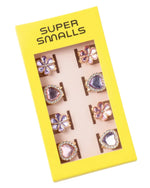 The Super Smalls "Love in Bloom Hair Clips" set comes in a yellow box with a clear window showing matching heart-shaped clips and includes eight colorful adjustable rings with heart and flower designs.