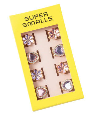 The Super Smalls "Love in Bloom Hair Clips" set comes in a yellow box with a clear window showing matching heart-shaped clips and includes eight colorful adjustable rings with heart and flower designs.