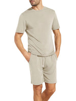 A person wearing a matching Eberjey Henry Short PJ Set made from temperature-regulating TENCEL™ Modal stands with hands in pockets against a white background.