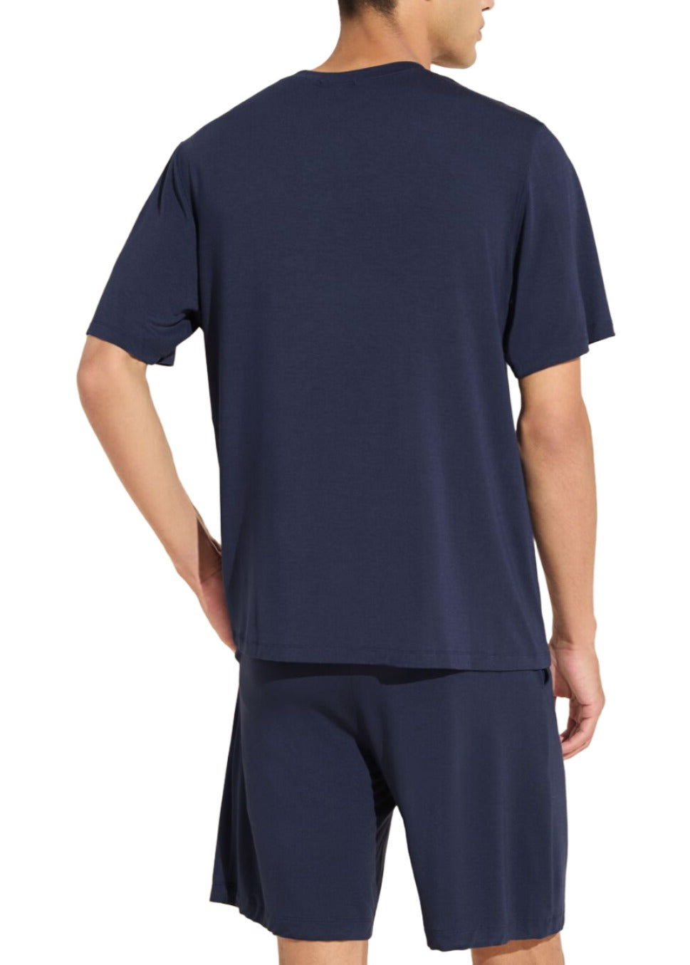 A person is shown from the back, wearing a navy blue short-sleeved shirt and matching shorts made from TENCEL™ Modal, offering a stylish yet comfortable look in the Eberjey Henry Short PJ Set by Eberjey.