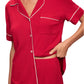 The individual is dressed in the Eberjey Gisele Relaxed Short PJ Set, a luxurious knit fabric set in red with white trim. It includes a short-sleeve button-up top and shorts, crafted from TENCEL™ Modal for exceptional softness and easy maintenance as it is machine washable.