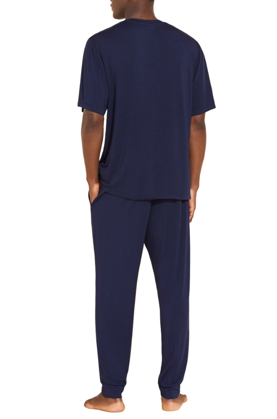 A person stands barefoot, facing away, wearing the Eberjey Henry Long PJ Set in dark blue, featuring a short-sleeve shirt and matching pants with an elastic waistband.