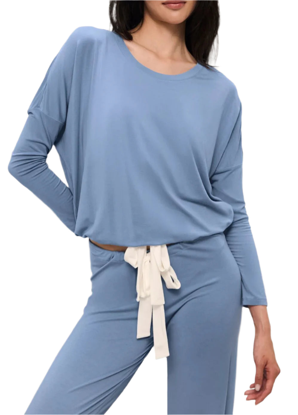 A woman wears the Eberjey EBJ Gisele Slouchy Set, a light blue, long-sleeve lounge set with wide sleeves, a white tie belt at the waist, and temperature-regulating knit fabric, standing with one hand on her hip.