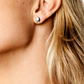 Close-up image of a person's ear adorned with a small, rounded silver stud earring from the LIÉ STUDIO Luna Earrings by Lie Studio. The person has blonde hair.