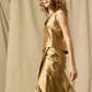 A person with curly hair wears the Ann Mashburn Gia Silk Shantung Top and matching skirt, standing against a beige fabric backdrop.