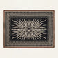 The Golden Horizon Pareo by Johanna Ortiz features a black background with a central beige sunburst and geometric borders—an eye-catching accessory to elevate your style, as versatile and striking as a chic scarf or wrap.