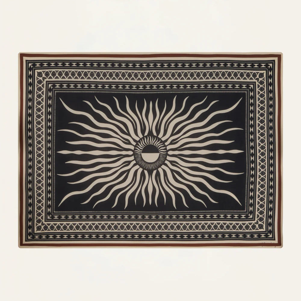 The Golden Horizon Pareo by Johanna Ortiz features a black background with a central beige sunburst and geometric borders—an eye-catching accessory to elevate your style, as versatile and striking as a chic scarf or wrap.