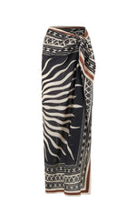 The Golden Horizon Pareo by Johanna Ortiz features a black and beige geometric and zebra stripe pattern in a wrap style with a side knot—ideal for styling as a skirt or versatile scarf.