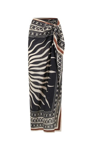 The Golden Horizon Pareo by Johanna Ortiz features a black and beige geometric and zebra stripe pattern in a wrap style with a side knot—ideal for styling as a skirt or versatile scarf.