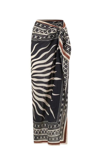 The Golden Horizon Pareo by Johanna Ortiz features a black and beige geometric and zebra stripe pattern in a wrap style with a side knot—ideal for styling as a skirt or versatile scarf.
