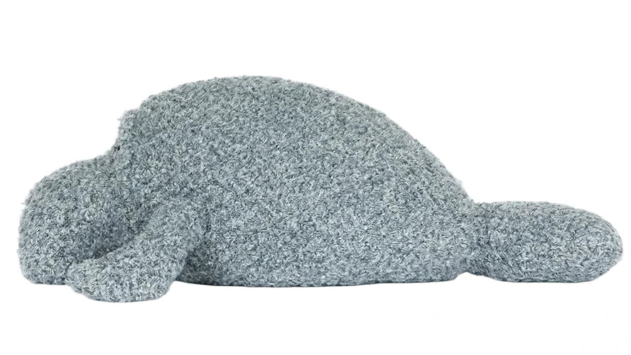 The Jellycat Maffles Manatee, a gray, textured seal-shaped plush pillow, rests on a white background—ideal for anyone seeking cozy comfort after experimenting with underwater candles and waterproof wicks.