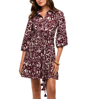 A woman wears the Figue Marcy Dress, a maroon and white patterned shirt dress with a collar, three-quarter sleeves, and a tie belt at the waist.