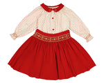 The Antoinette Girls' Marie Red Floral Smocked Skirt and Blouse Set features a cream long-sleeved handmade blouse with a red collar, red buttons, and a bright red corduroy skirt with floral embroidery at the waist.
