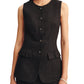A woman wearing the POSSE Matilda Gilet, a premium linen sleeveless black vest with hip pleats, paired with a matching skirt, stands with her hands at her sides.