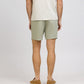 A person is shown from the back against a plain background, wearing a light beige t-shirt, Onia Air Linen Pull-On Short with a stretch waist and back pocket, and tan espadrille shoes.