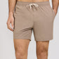 A person wearing light brown Onia Land to Water Short 6" with four-way stretch, hands in pockets, shown from mid-torso to mid-thigh against a plain background.