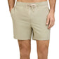 A person wearing Onia Land to Water Short 6" in light beige, featuring a drawstring waistband and side pockets, stands with one hand in a pocket.