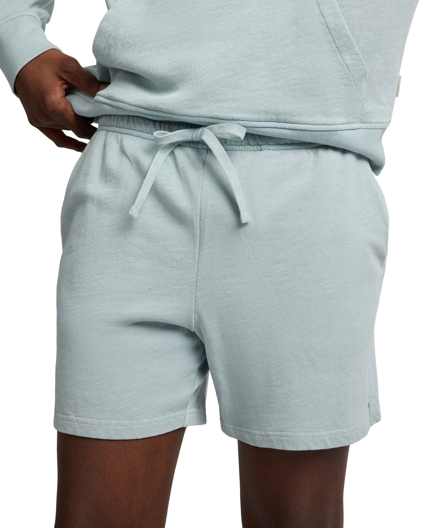 A person in Onia’s Slub Terry Short and matching hoodie, one hand on the waistband—an effortless lounge essential.