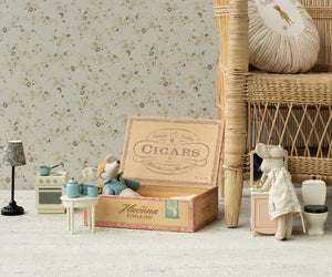 Maileg Mum & Dad Mice in Cigarbox stand in a cozy miniature room with a wicker chair, stove, sink, lamp, and their vintage-style cigar box bed.