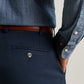 Navy Peter Millar Signature Sateen Flat Front Trouser in stretch cotton with a single button-closure back pocket and a brown leather belt, worn with a blue button-down shirt.